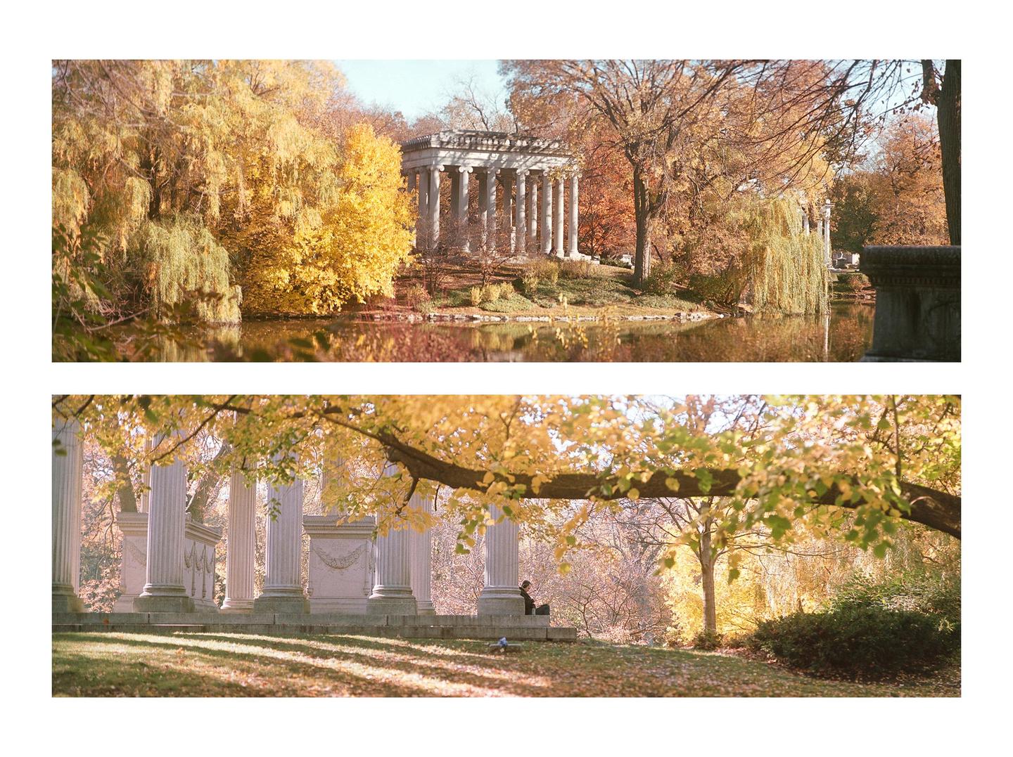 A classical stone structure with columns stands by a body of water, surrounded by trees with golden autumn foliage.