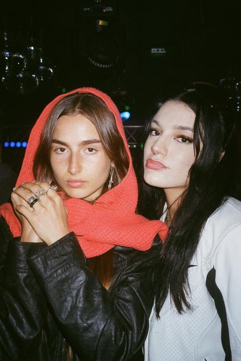 Two women pose for a photo in a dimly lit room with disco balls in the background.