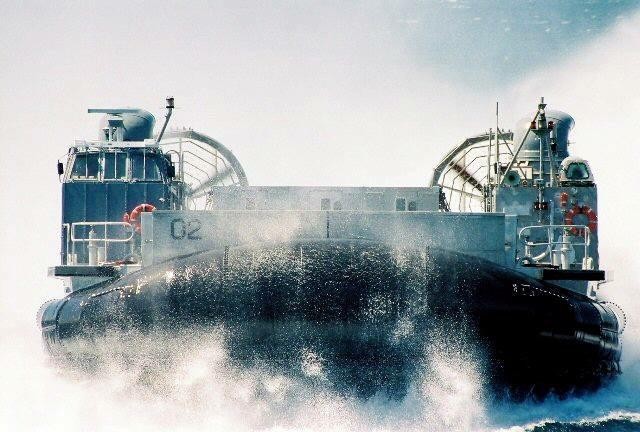 A hovercraft with the number 02 on its side moves through water, creating a large spray.
