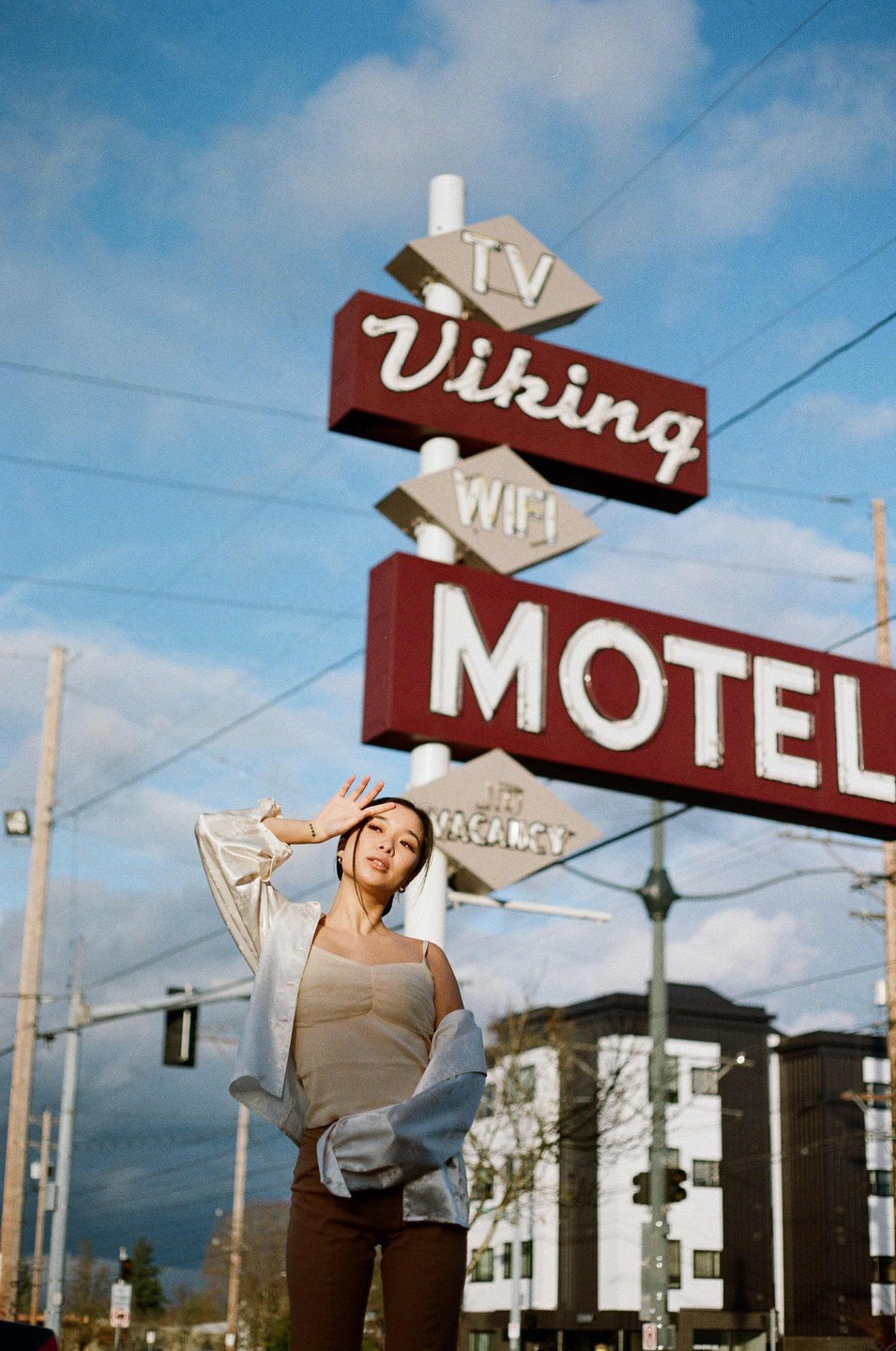 A woman stands in front of a motel sign that reads "Viking Motel" and "Vacancy."