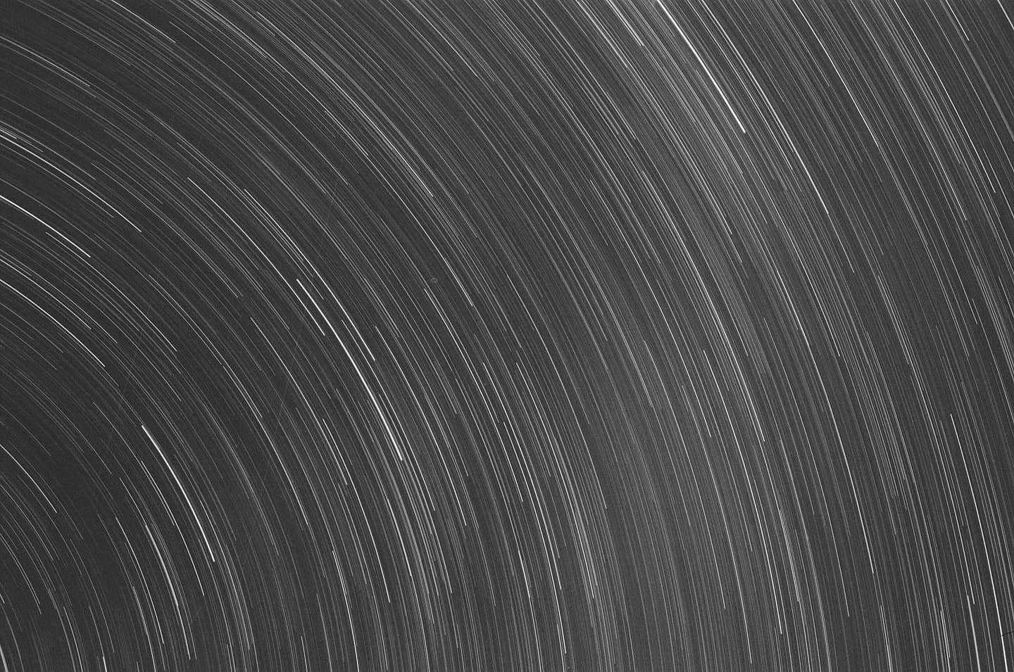 White star trails arc across a dark night sky.