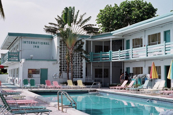 A swimming pool with lounge chairs and umbrellas is next to the International Inn.