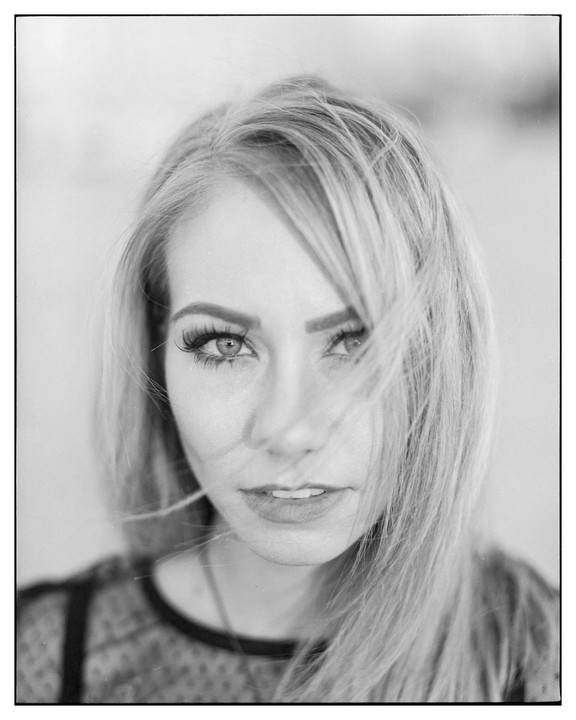 A woman with long hair looks directly at the viewer.