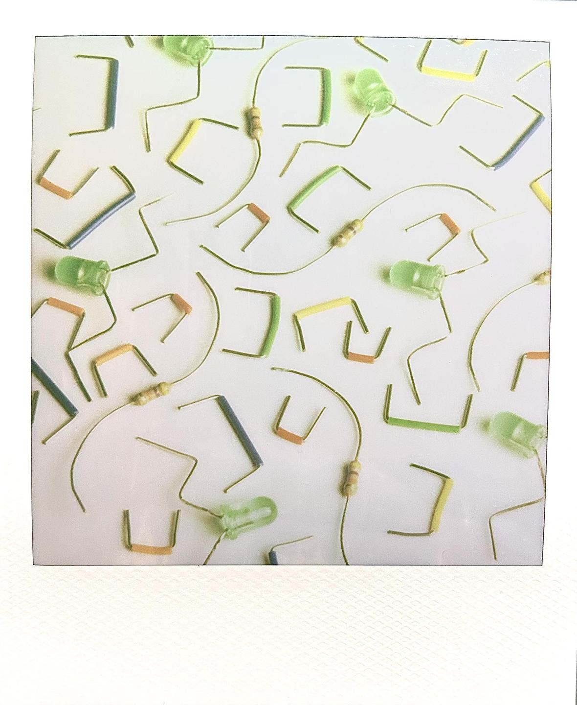 A collection of electronic components, including jumpers, resistors, and diodes, are scattered across a white surface.