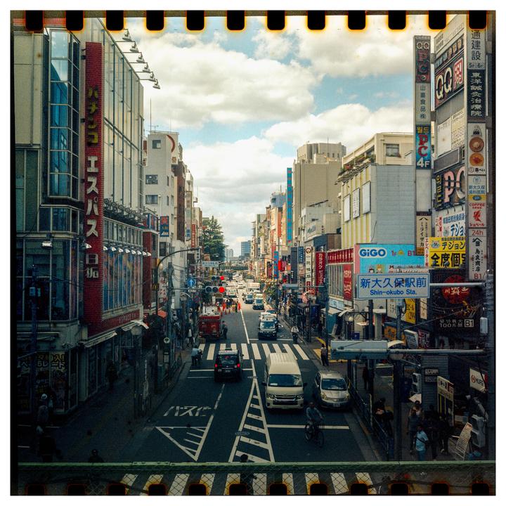 A busy street in Tokyo is filled with cars, pedestrians, and buildings with many signs.