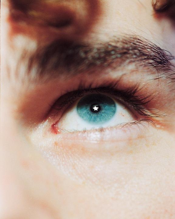 A close-up shows a blue eye with a star-shaped reflection in the pupil.