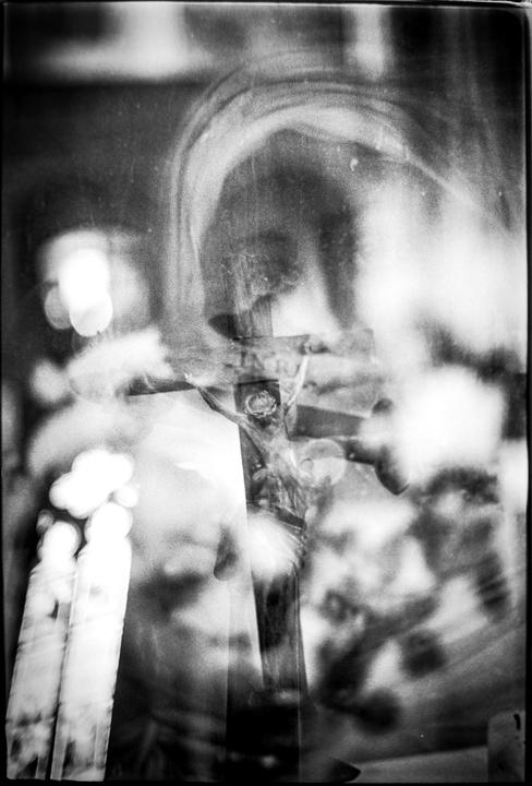 A crucifix is visible through multiple exposures, creating a hazy and layered effect.