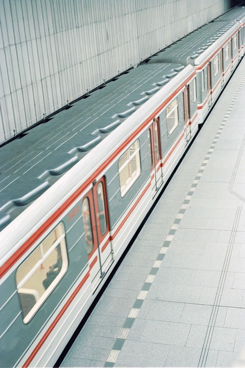 A subway train with red doors and a grey body is stopped at a station platform.