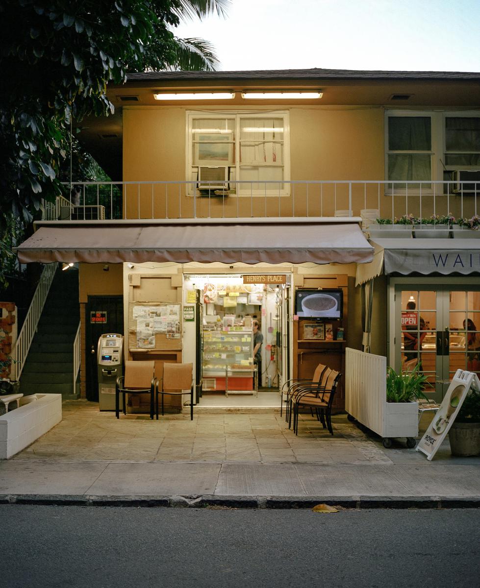 A small shop with an awning and a brightly lit interior is visible from the street.