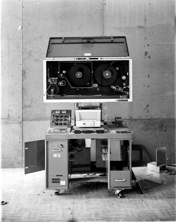 An enlarger with its top open, revealing two large reels, sits on a cart with various controls and a printer.