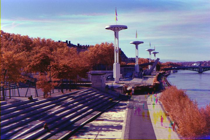 A wide view shows a river, a bridge, a promenade, and a large set of steps, all lined with trees and modern light fixtures.