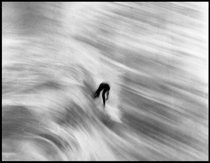A surfer rides a wave, captured with motion blur.