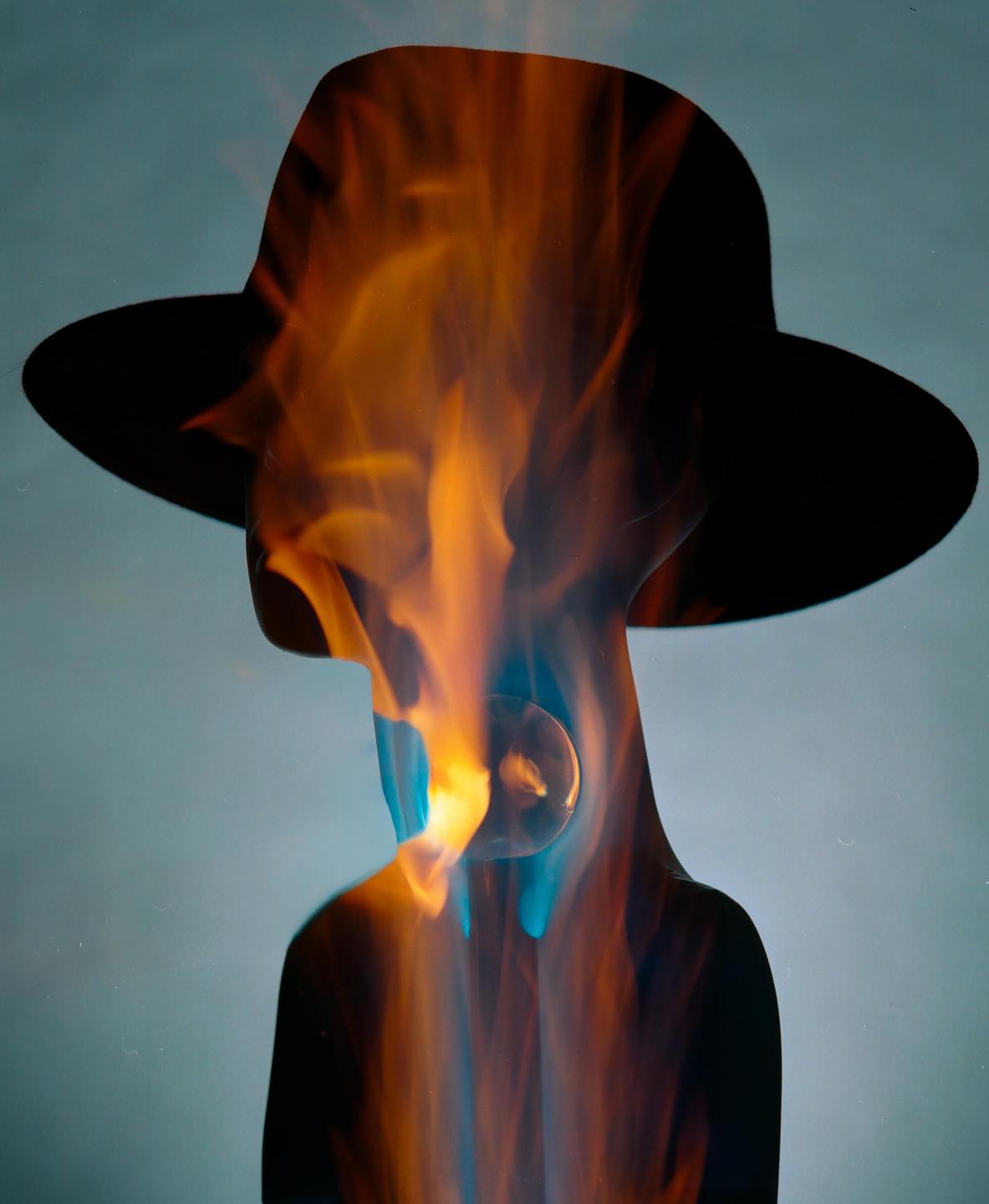 A silhouette of a person wearing a hat is filled with orange and blue flames.