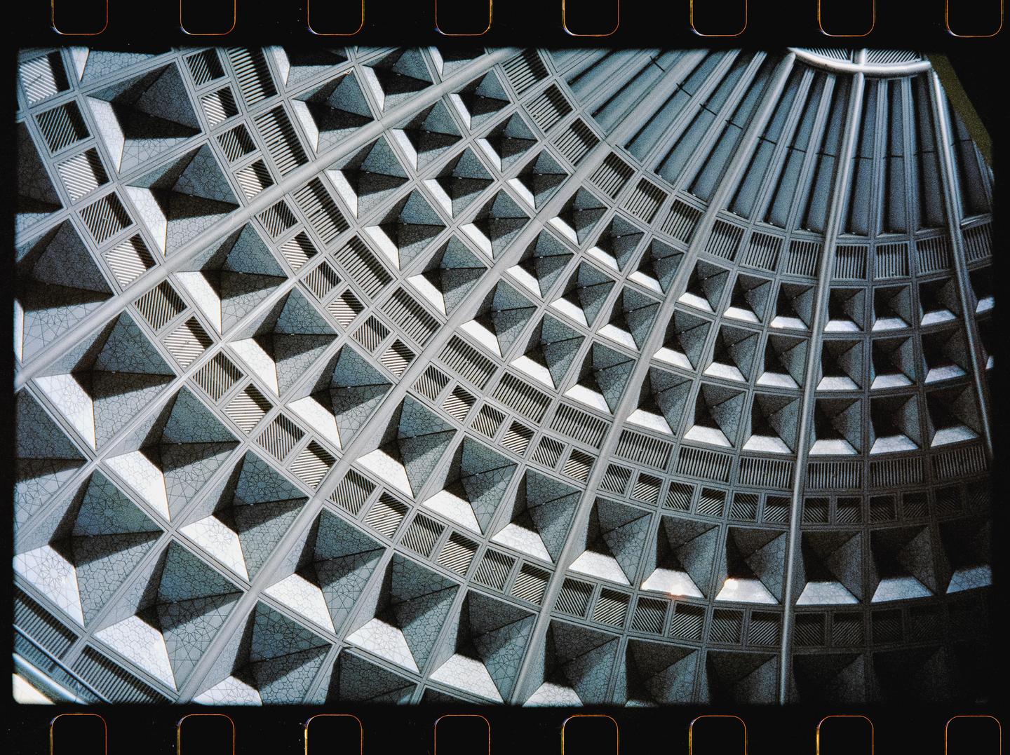 A detailed view of the geometric pattern on the ceiling of a building is shown.