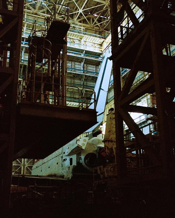 A space shuttle is visible inside a large hangar with scaffolding and structural beams.