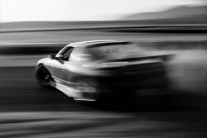 A car drifts on a track, creating a cloud of smoke behind it.