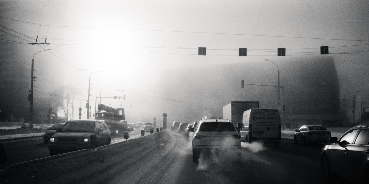 Cars drive on a city street on a frosty morning.