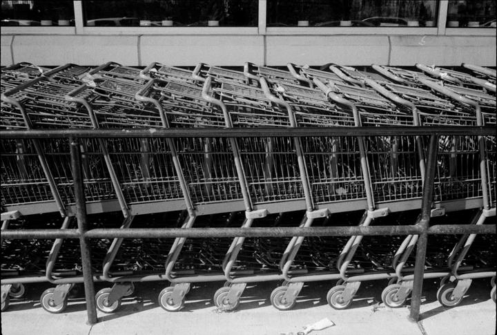 A line of shopping carts are parked outside a building with a window.