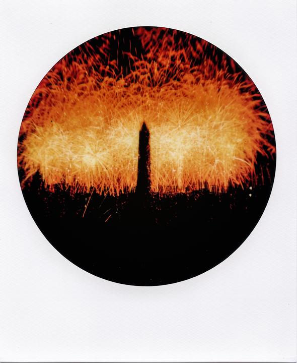 Fireworks explode behind the Washington Monument at night.