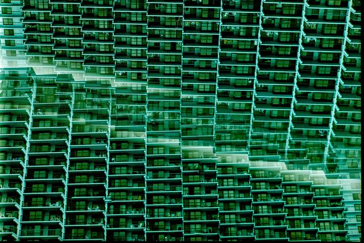 A green-tinted image shows a tall building with many balconies and windows, with a double exposure effect.