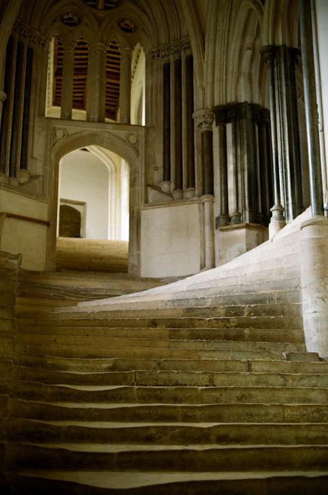 A stone staircase curves upwards towards an arched doorway in an ancient building.