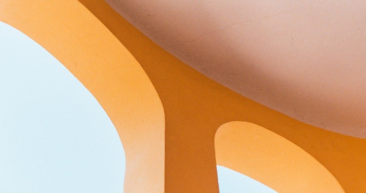A light blue wall is partially covered by a large orange archway with shadows.