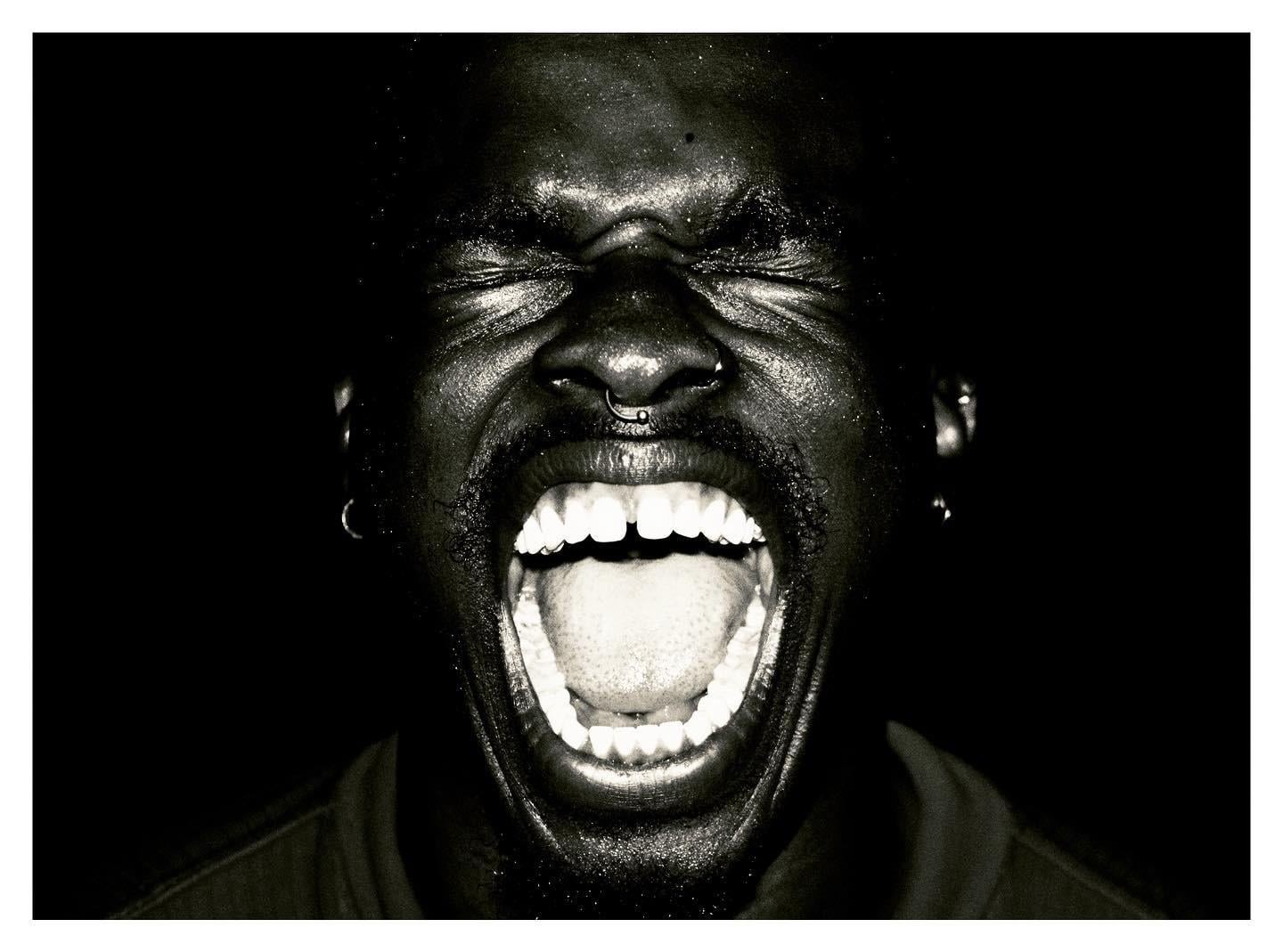 A man with his eyes closed and mouth wide open is screaming.