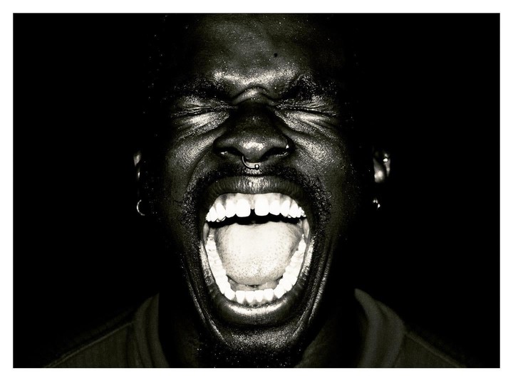 A man with his eyes closed and mouth wide open is screaming.
