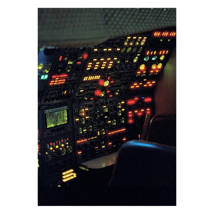 The cockpit of a Concorde airplane is illuminated by many glowing buttons and screens.