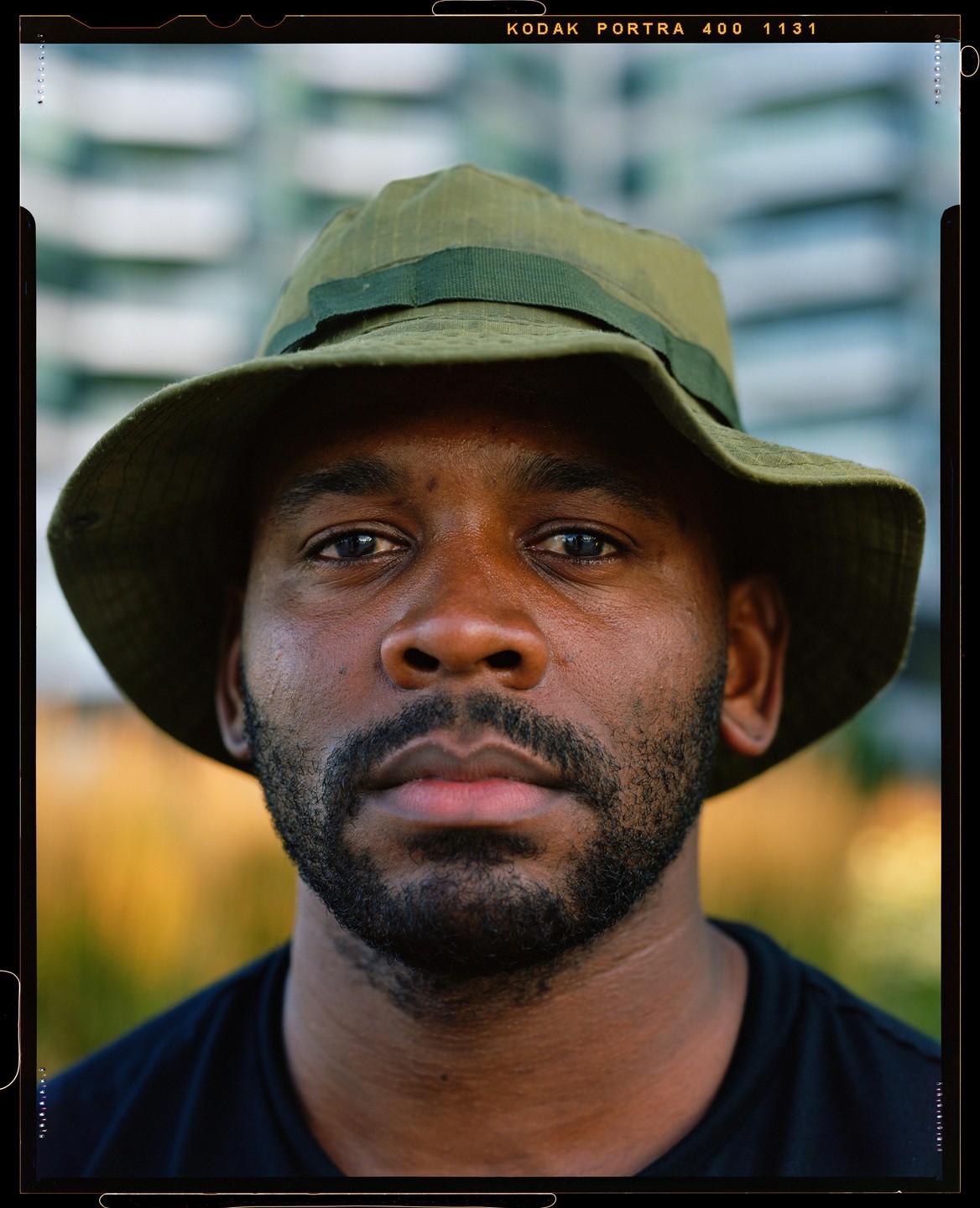A man wearing a green bucket hat looks directly at the viewer.