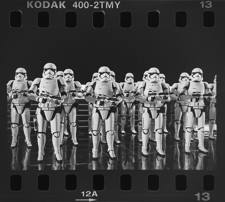 A group of stormtroopers stand in formation on a reflective surface.