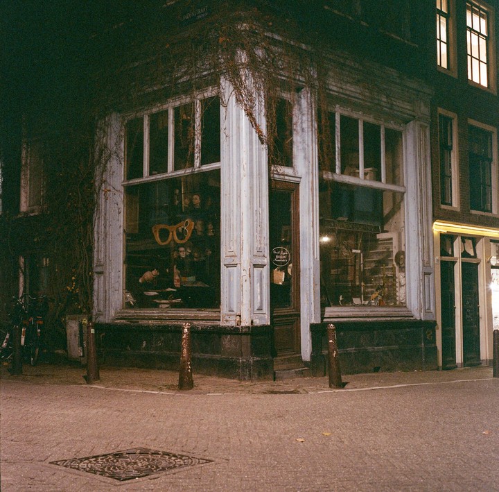 A corner building with large windows and vines growing on its facade is illuminated at night.