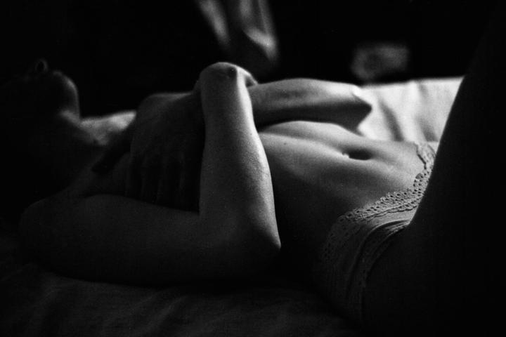 A woman lies on her back with her arms crossed over her chest, wearing lace underwear.