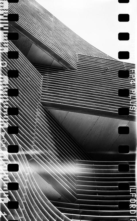 A modern building with horizontal lines and curves is shown in black and white.