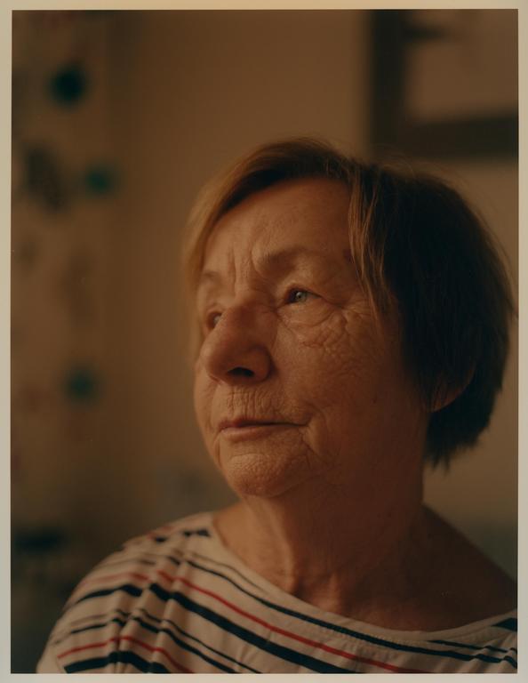 A woman with short hair and a striped shirt looks to the side.