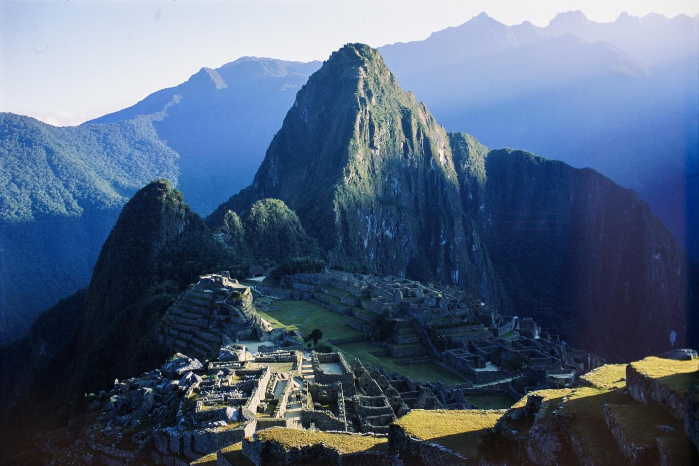 An ancient city is nestled among mountains under a clear sky.