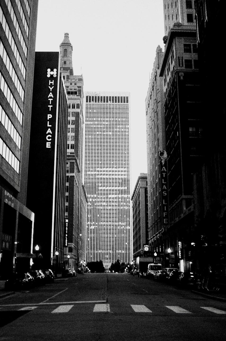 A street is visible between tall buildings with a crosswalk in the foreground.