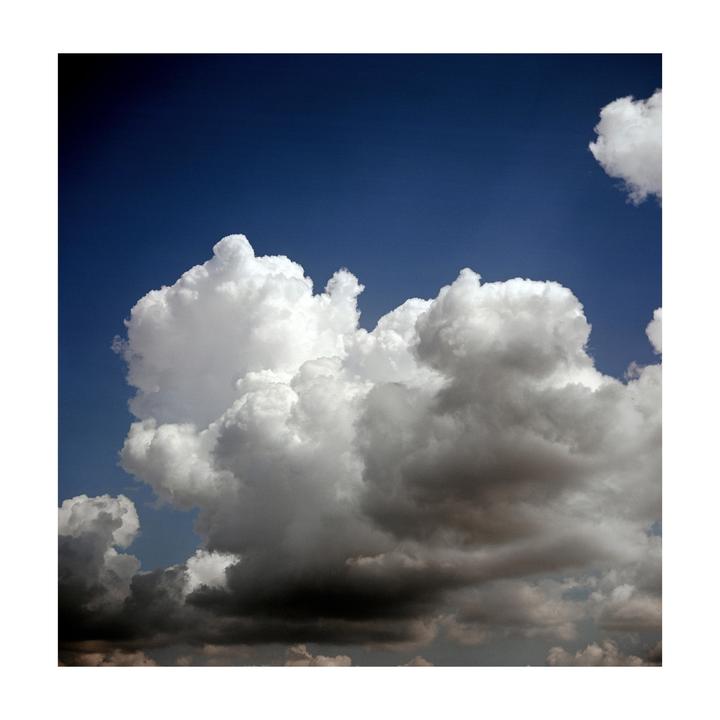 A large, fluffy white cloud is visible against a deep blue sky, with darker clouds below.