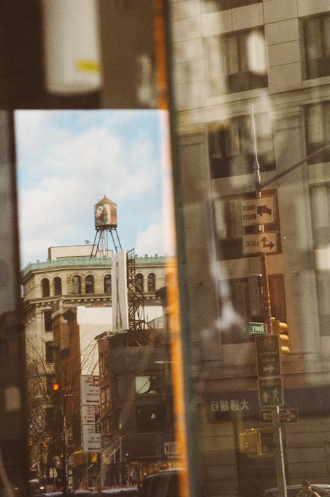 A water tower with a woman's portrait is visible above buildings in a city.