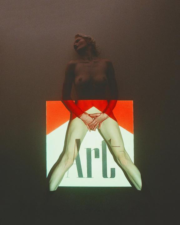 A woman stands with a red and white graphic projected onto her lower body, covering her with the word "Art."