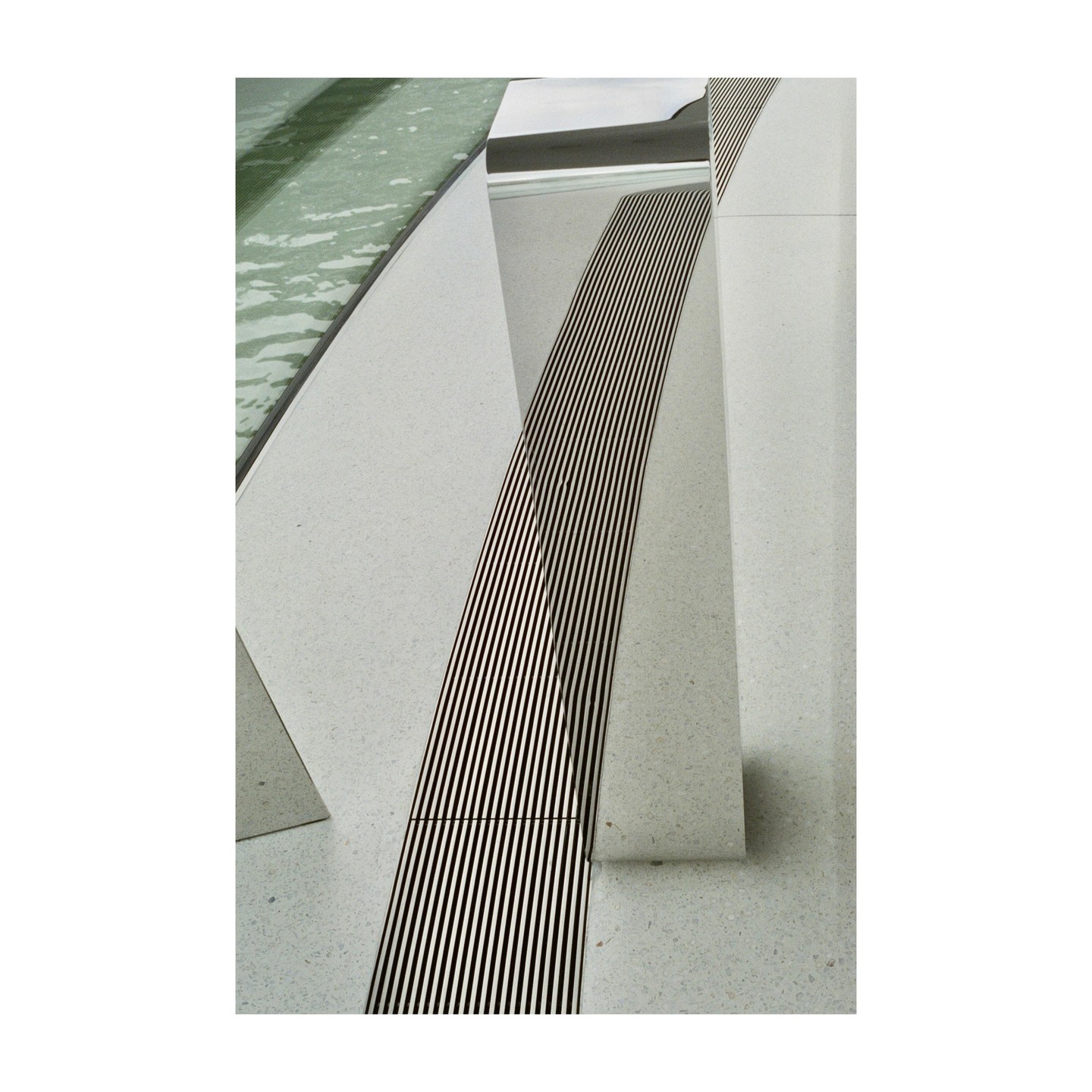 A close-up view shows a water feature with a metal grate and light-colored stone.