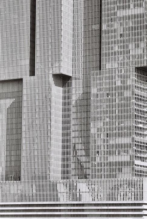 A tall building with many vertical lines and a few horizontal elements is shown in a black and white architectural photograph.