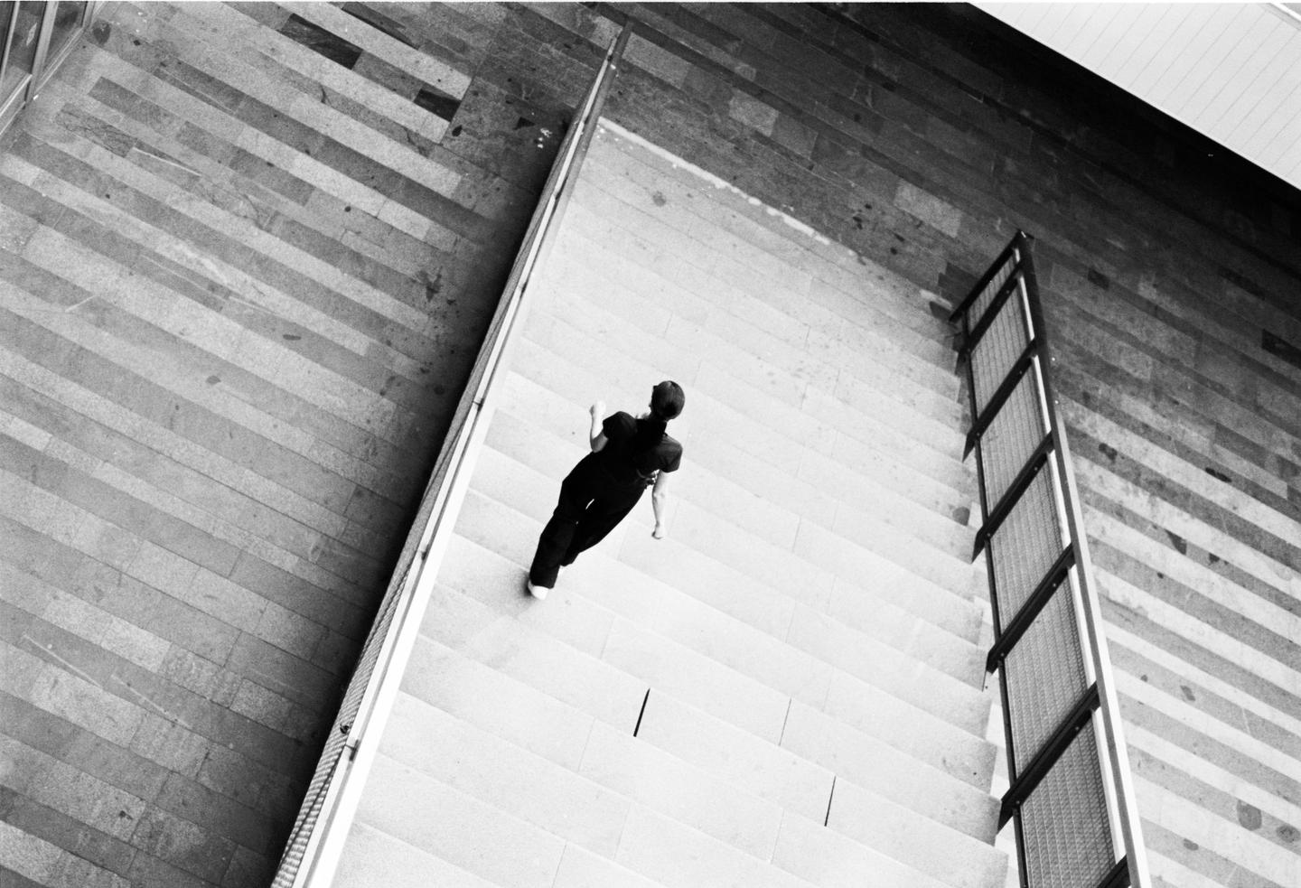A person walks down a flight of stairs next to a textured wall.