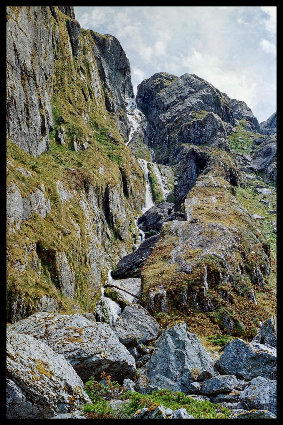 A waterfall cascades down a rocky, moss-covered mountain.