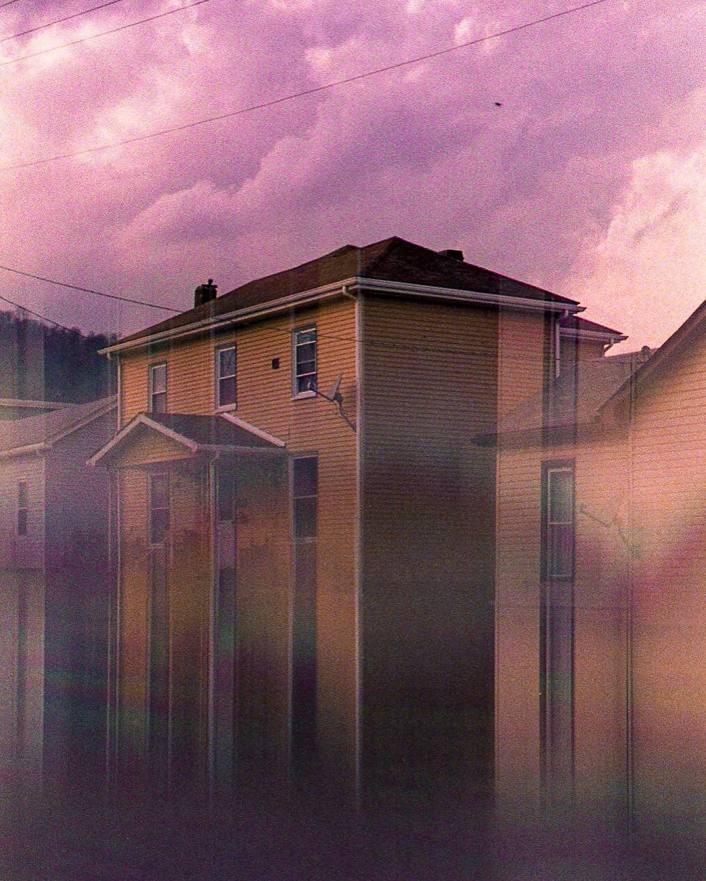 A house stands under a vibrant purple sky with power lines visible above.