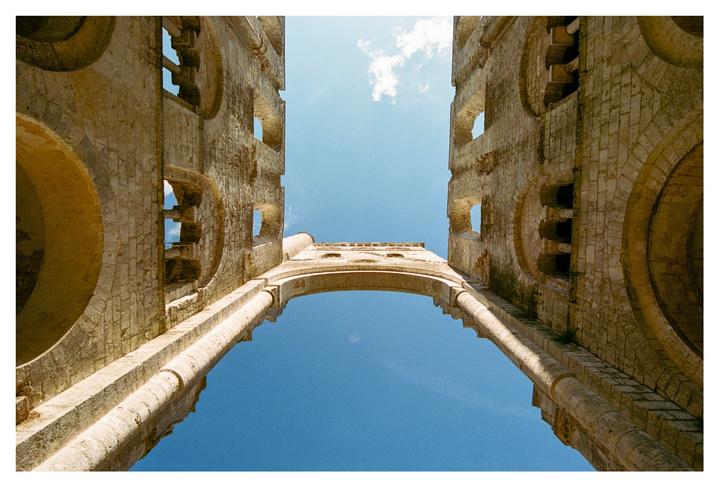 A low-angle view shows the ruins of an abbey against a bright blue sky.