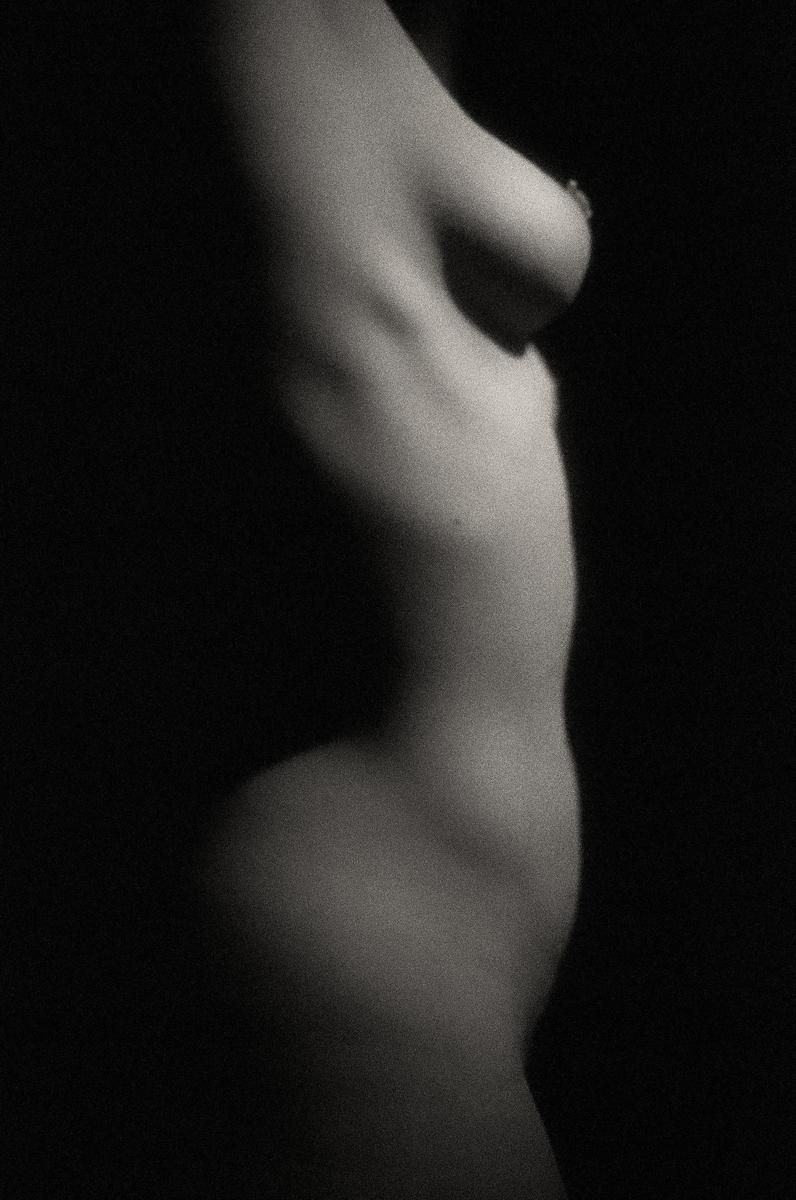 A woman's torso is visible in profile against a dark background.