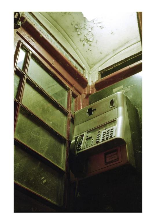 A payphone is visible inside a booth with peeling paint on the ceiling.