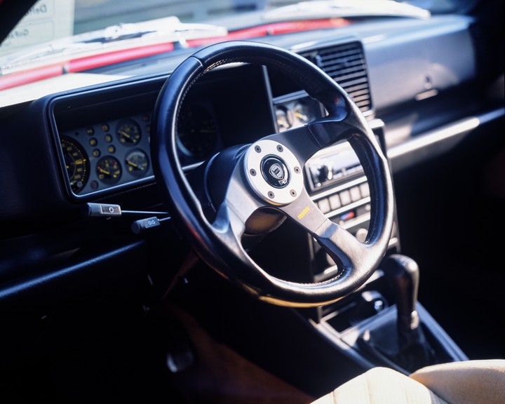 The interior of a car shows the steering wheel, dashboard, and gear shift.