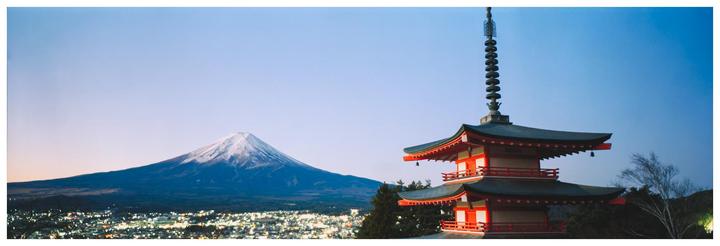 A pagoda stands in the foreground with Mount Fuji and a city at its base in the background.